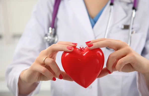 Läkare med stetoskop undersöka rött hjärta — Stockfoto
