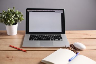 Laptop ahşap bir masada duruyor.