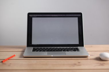 Laptop ahşap bir masada duruyor.