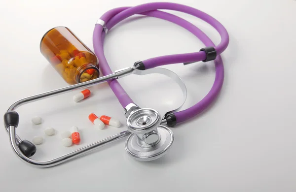 Comprimidos, comprimidos e estetoscópio sobre fundo branco — Fotografia de Stock