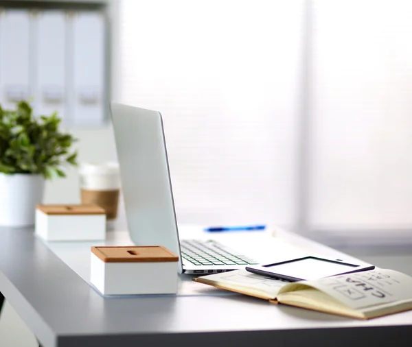 Office table with blank notepad and laptop