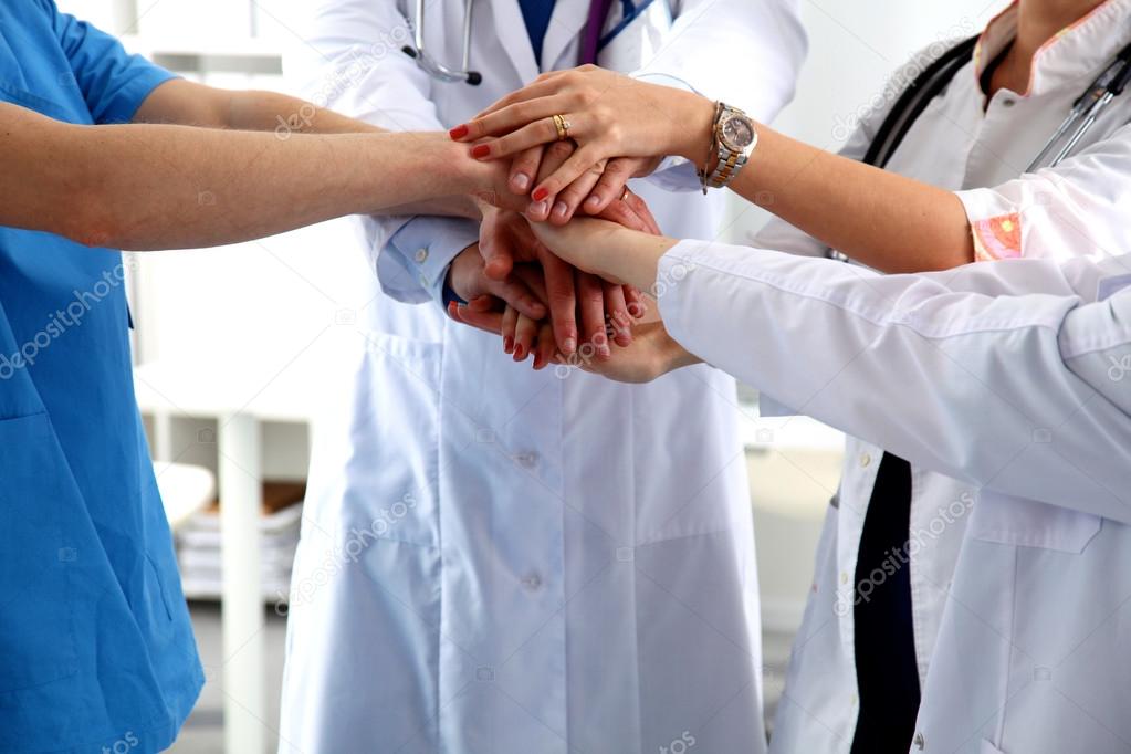 Group of doctors joining hands with low angle view