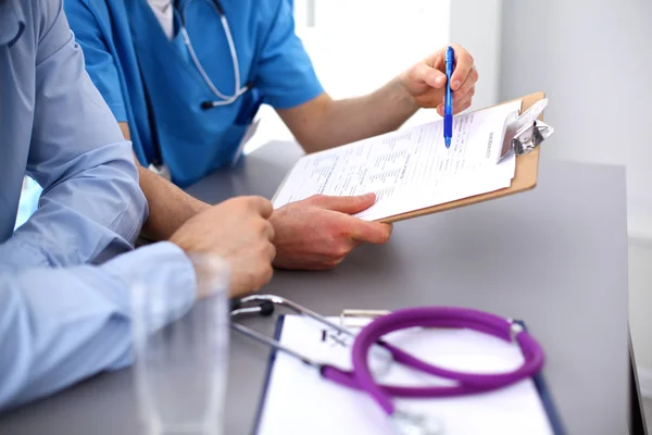 Медичний лікар сидить за столом і дивиться пацієнтам рентген — стокове фото