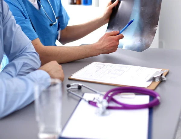 Läkare sitter vid bord och ser patienter roentgen — Stockfoto