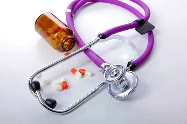 Таблетки, таблетки та стетоскоп на білому тлі — стокове фото