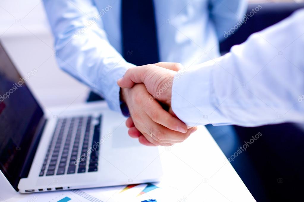 Business meeting at the table shaking hands conclusion of the contract