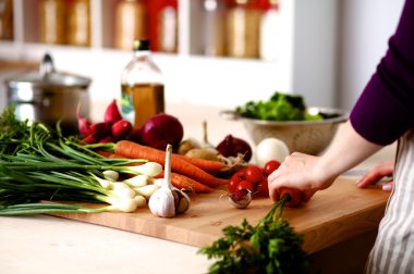 Mutfakta sebze doğrayan genç bir kadın.