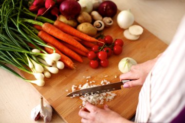 Mutfakta sebze doğrayan genç bir kadın.