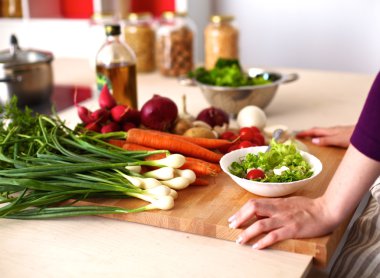 Mutfakta sebze doğrayan genç bir kadın.