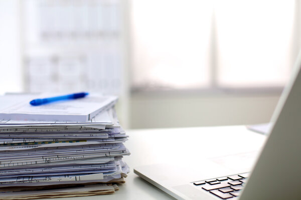 Stack of papers and glasses lying on table desaturated