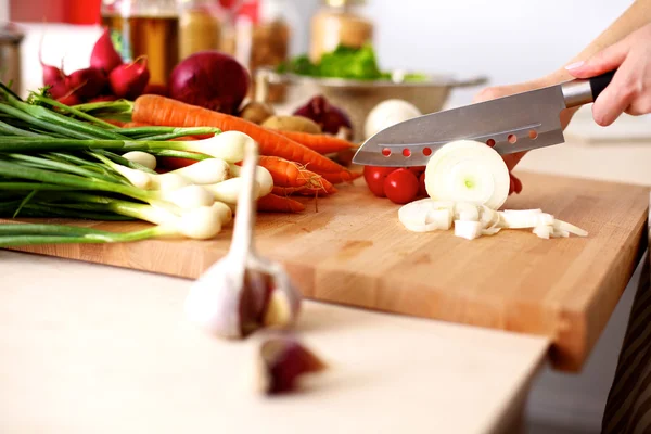 Jovem mulher cortando legumes na cozinha — Fotografia de Stock