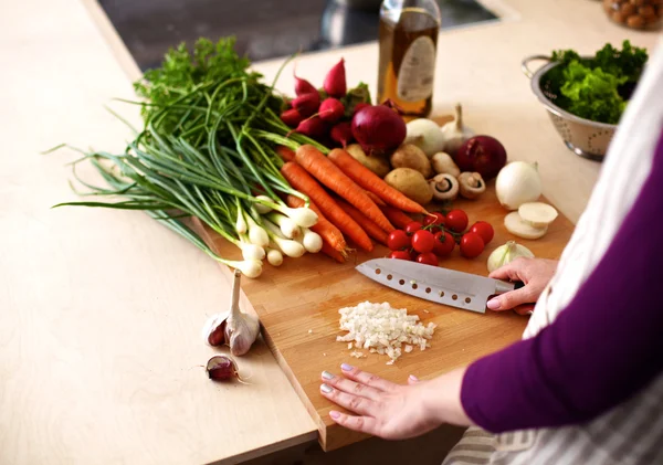 Mutfakta sebze doğrayan genç bir kadın.