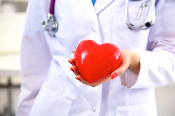 Kvinna läkare med stetoskop håller hjärtat, isolerad på vit bakgrund — Stockfoto