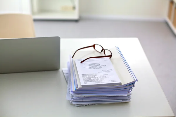 Notebook s hromadou složek na stole na bílém pozadí — Stock fotografie