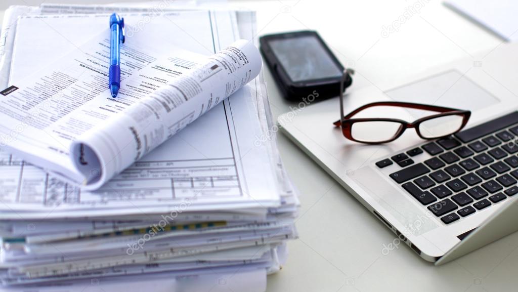 Laptop with stack of folders on table on white background