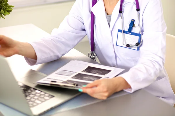 Hermosa joven sonriente doctora sentada en el escritorio — Foto de Stock