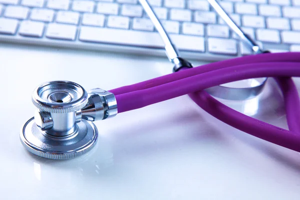 Medicinsk stetoskop nära en laptop på ett träbord, på vitt — Stockfoto