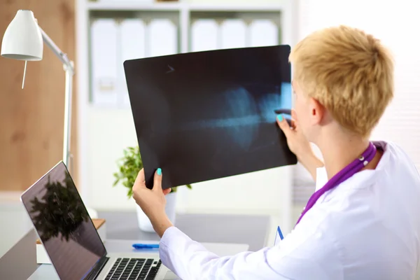 Beautiful young smiling female doctor sitting at the desk — Stock Photo, Image