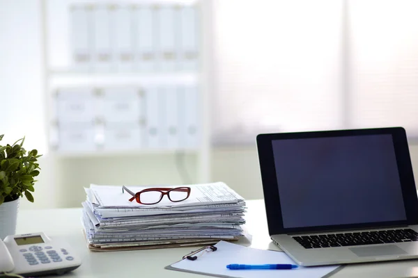 Laptop mit Ordnerstapel auf Tisch auf weißem Hintergrund — Stockfoto