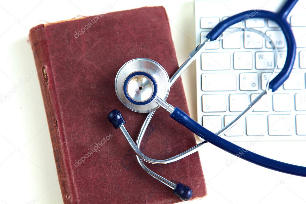 Medical stethoscope with books and laptop on table