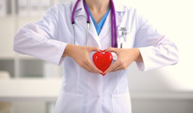 Genç kadın doktor ofisinde kırmızı bir kalp tutan