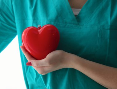 Genç kadın doktor ofisinde kırmızı bir kalp tutan