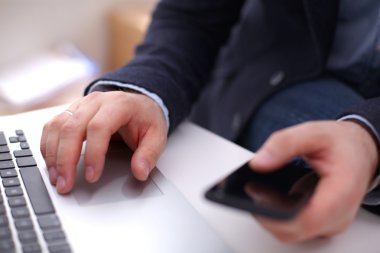 İşadamı onun işyerinde kullanan bir akıllı telefon ve dizüstü