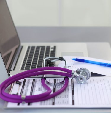 Beyaz ahşap bir masa üstünde a laptop yanında sağlık stetoskop