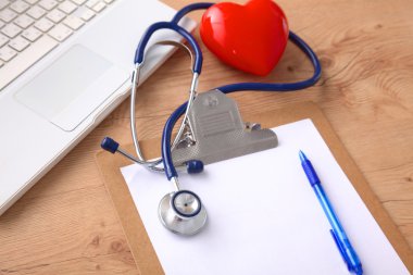 Beyaz ahşap bir masa üstünde a laptop yanında sağlık stetoskop
