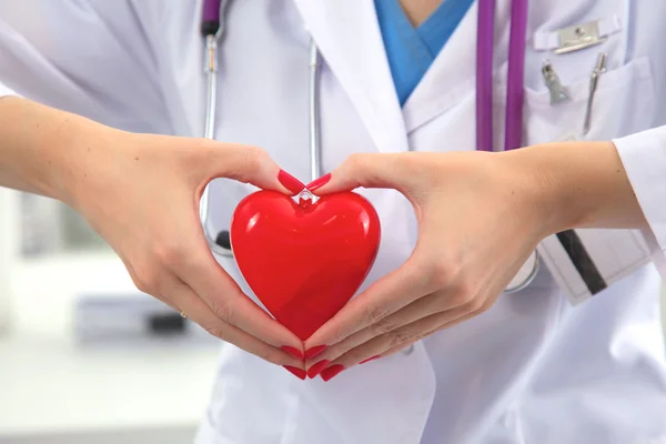 Ung kvinna läkare håller ett rött hjärta, i office — Stockfoto