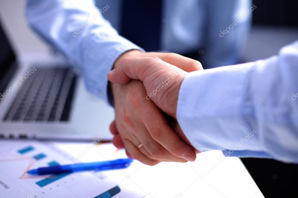 Business handshake. Two businessman shaking hands with each other in the office
