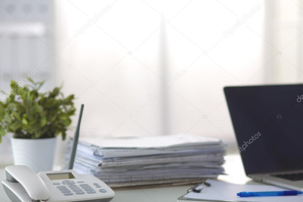 Laptop with stack of folders on table on white background