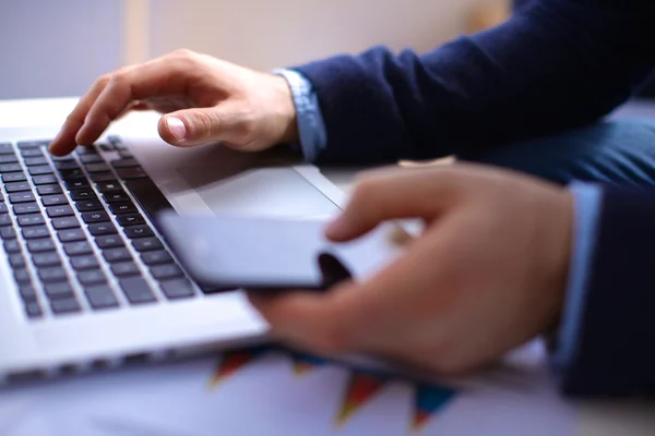 Businessman at his workplace uses a smartphone and laptop — Stock Photo, Image