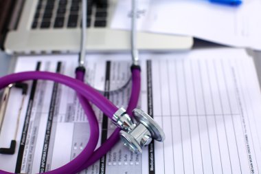 Beyaz ahşap bir masa üstünde a laptop yanında sağlık stetoskop