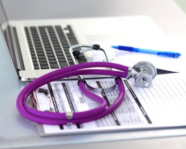 Beyaz ahşap bir masa üstünde a laptop yanında sağlık stetoskop