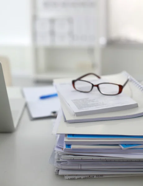 Laptop mit Ordnerstapel auf Tisch auf weißem Hintergrund — Stockfoto