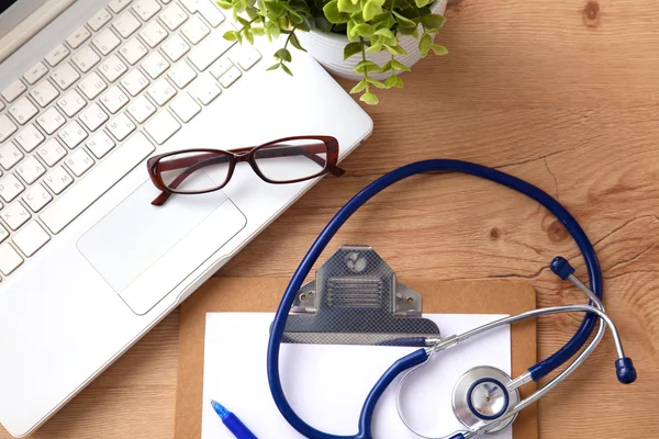 A medical stethoscope near a laptop on a wooden table, on white — Stock Photo, Image