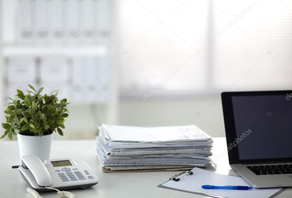 Laptop with stack of folders on table on white background