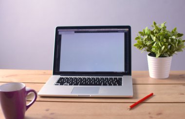 Laptop ahşap bir masada duruyor.