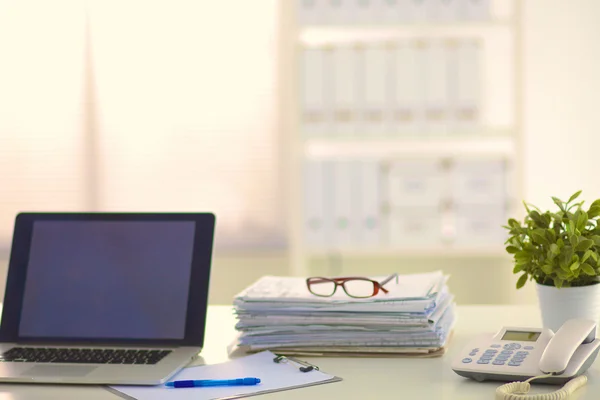 Laptop met stapel mappen op tafel op witte achtergrond — Stockfoto