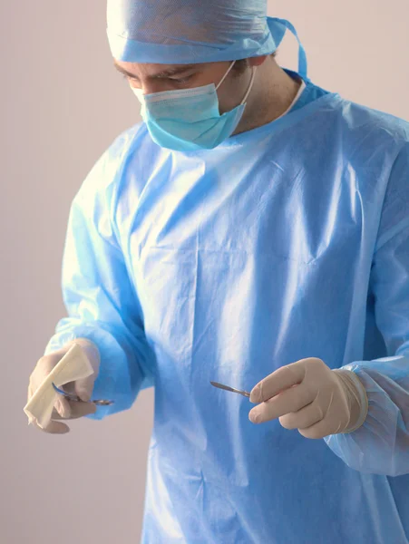 Homem cirurgião segura um bisturi em uma sala de cirurgia — Fotografia de Stock