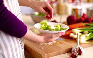 Mutfakta sebze doğrayan genç bir kadın.