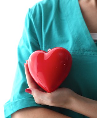 Genç kadın doktor ofisinde kırmızı bir kalp tutan