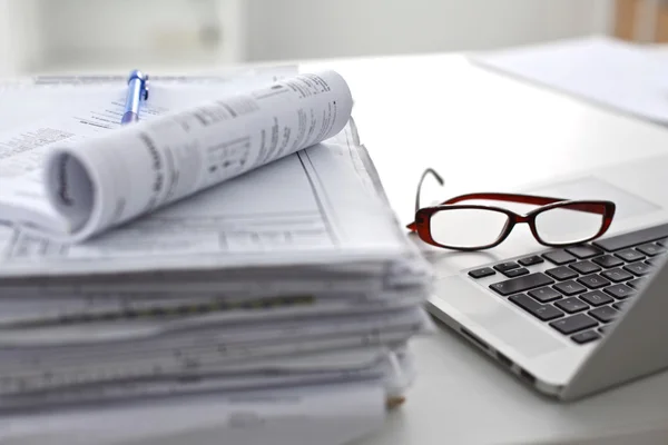 Laptop with stack of folders on table on white background — Stock Photo, Image