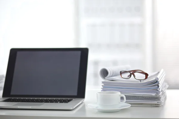 Laptop with stack of folders on table on white background — Stock Photo, Image