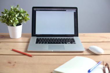 Laptop ahşap bir masada duruyor.