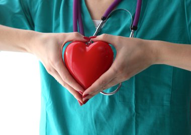 Genç kadın doktor ofisinde kırmızı bir kalp tutan