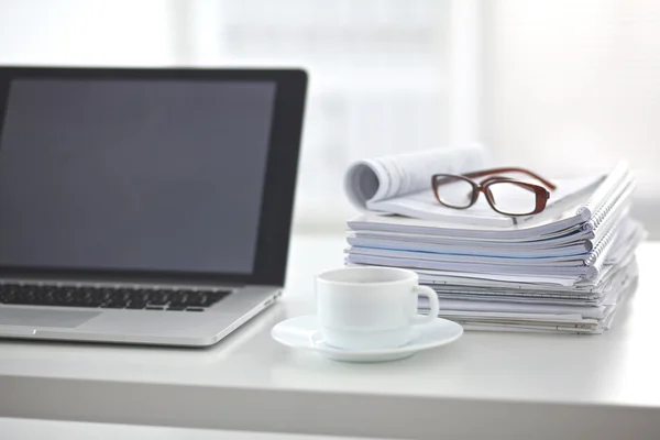 Laptop with stack of folders on table on white background — Stock Photo, Image