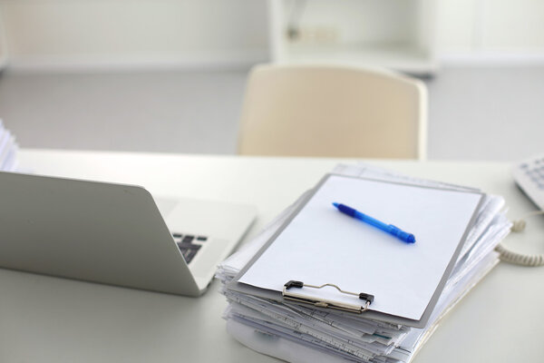 Laptop with stack of folders on table on white background