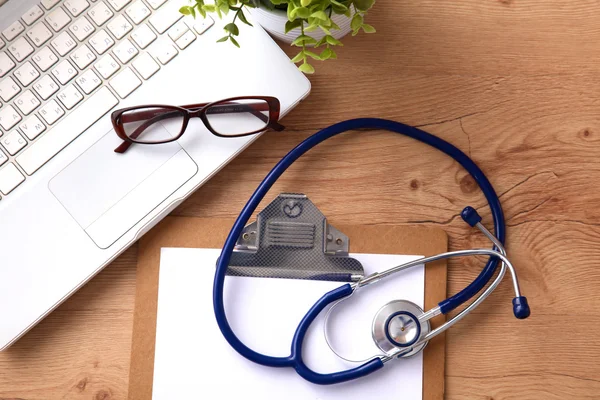 A medical stethoscope near a laptop on a wooden table, on white — Stock Photo, Image